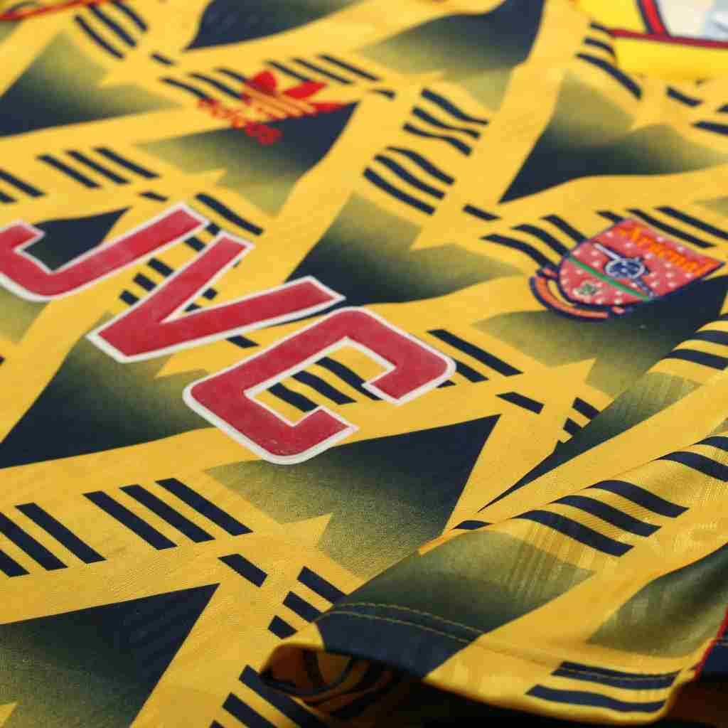Close up of a yellow Arsenal jersey with branding and patterns